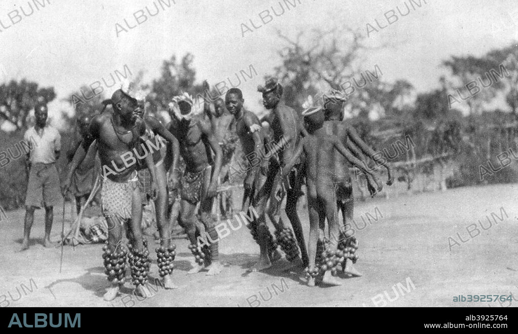 Ugandan dancers, Dodoma to Mongalla, Uganda, 1925 (1927). A print from Cape to Cairo, by Stella Court Treatt, George G Harrap & Company Ltd, 1927. The book was an account of the first successful journey by motor vehicle from Cape Town to Cairo, accomplished by Stella Court Treatt and her husband, Major Chaplin Court Treatt, in 1924-1926.