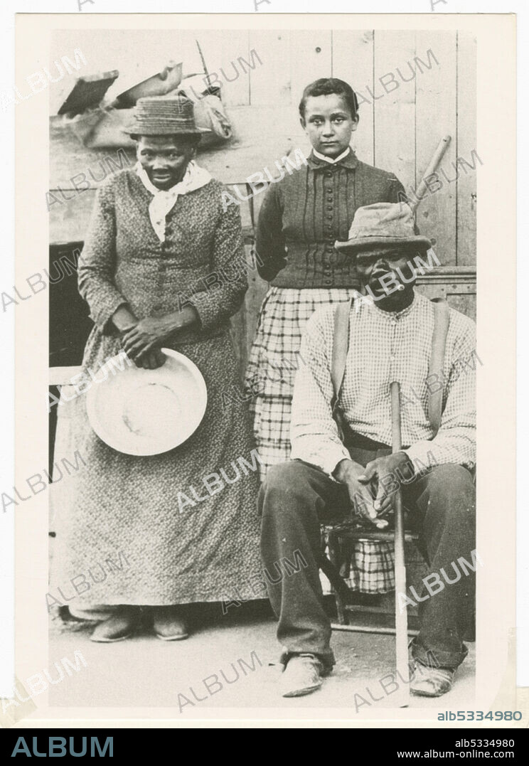 WILLIAM HAIGHT CHENEY. A black-and-white postcard featuring a photograph of Harriet Tubman, her husband Nelson Davis, and their adopted daughter Gertie. African-American anti-slavery activist Harriet Tubman (c1820-1913) was born into slavery in Maryland. She escaped in 1849, became a leading Abolitionist and was active as a 'conductor' in the Underground Railroad, the network which helped escaped slaves to reach safety. Tubman stands on the left holding a round pan. The postcard was sent to Mariline Wilkins in Philadelphia, PA from Sedalia Gaines in 1992.