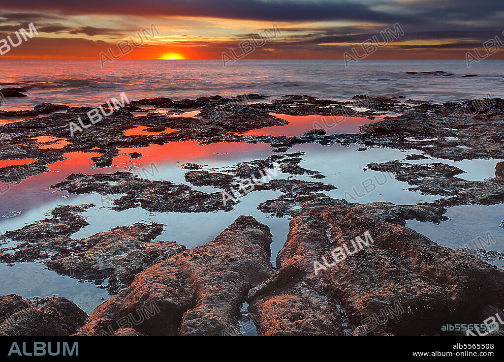 Tidal pools reflecting the sunrise colors at the southern hemisphere autumn equinox, Miramar, Argentina.