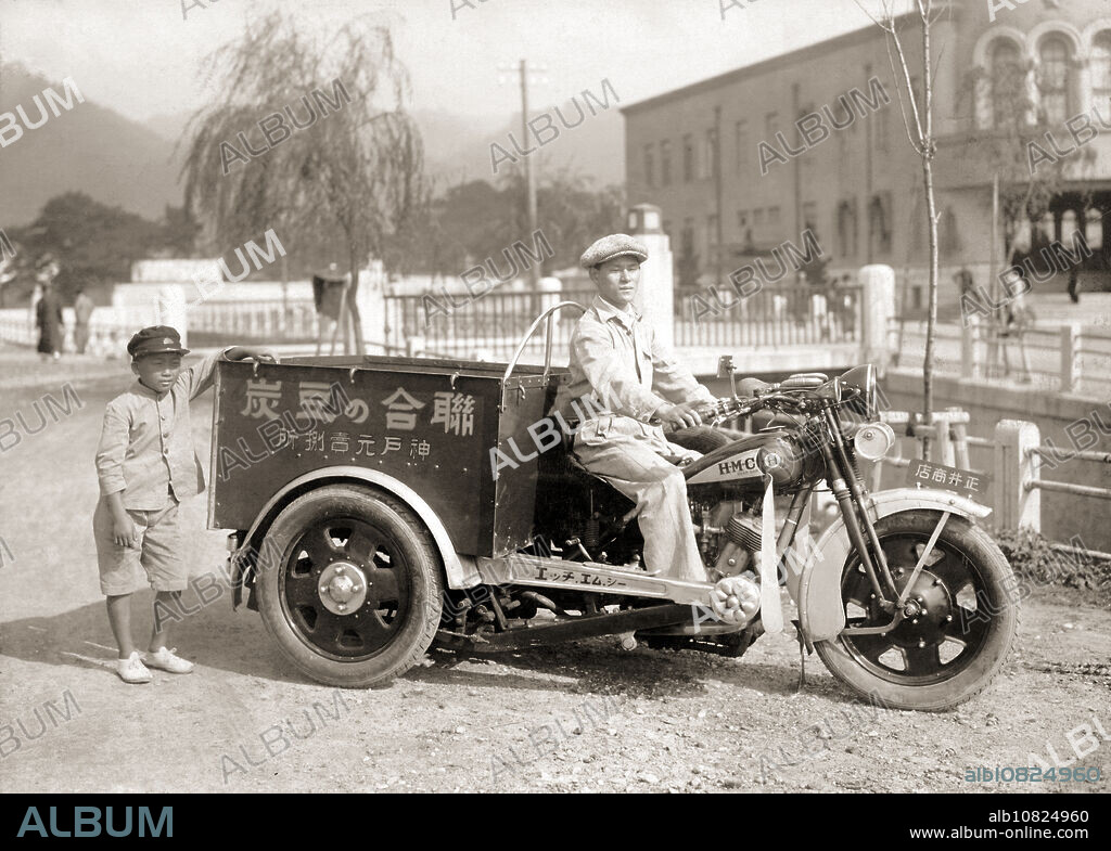 [ 1930 Japan - HMC Rear Car Motorcycle, Kobe ] A man selling charcoal briquettes poses on a rear car delivery motorcycle in Kobe. The motorcycle is a trike manufactured by the Hyogo Motors Company (HMC, ). No driver's license was needed for trikes below 750cc, making them extremely popular in Japan. The photo is dated May 12, 1930. Very few Japanese cargo trikes survived the war, making this photo an important historical document. 20th century gelatin silver print.