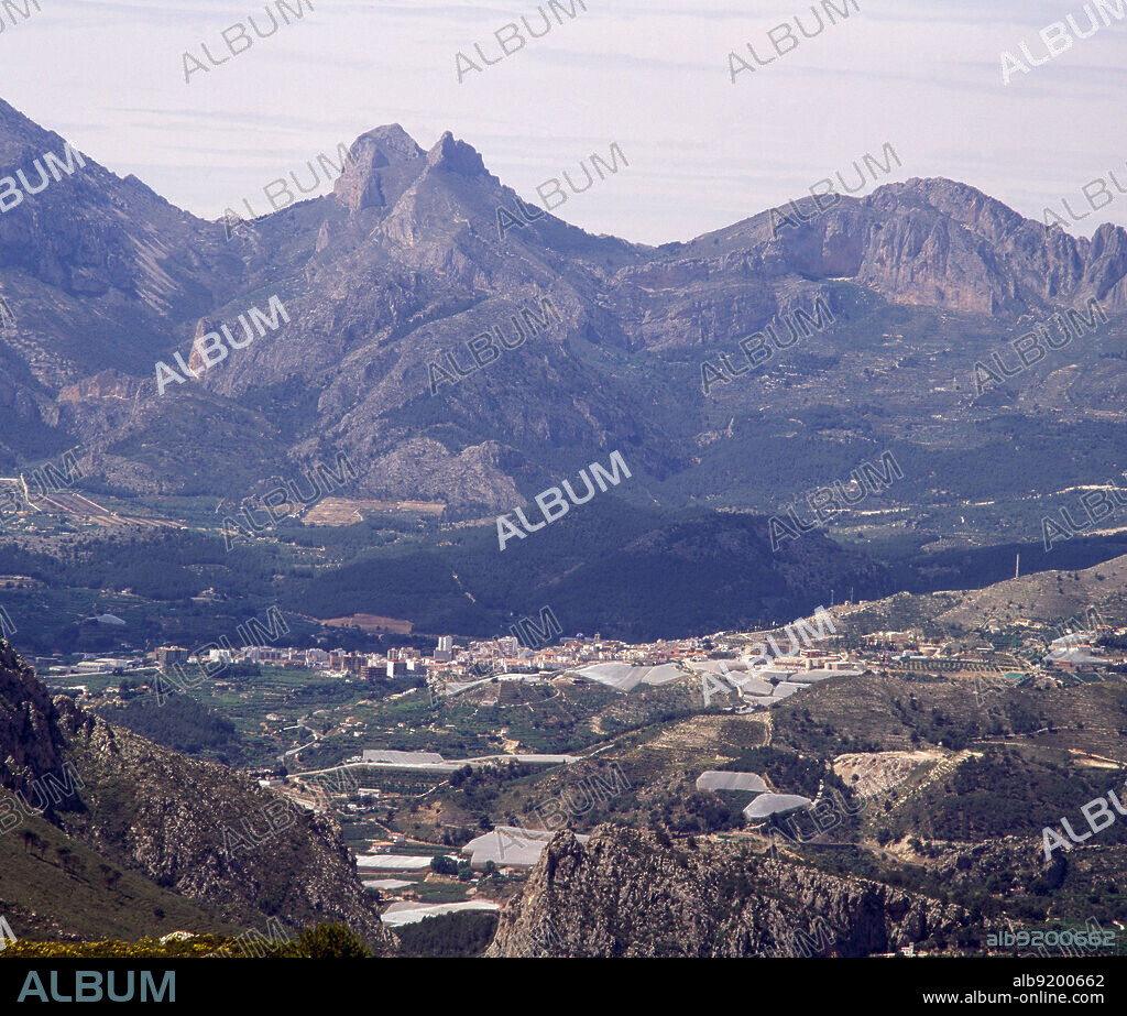 PAISAJE MONTAÑOSO - PUEBLO EN EL VALLE - INVERNADEROS DE NISPEROS  - FOTO AÑOS 90.