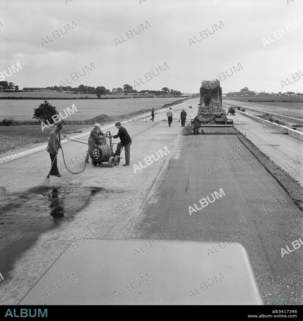 JOHN LAING PLC. A view of the construction of the Birmingham to Preston Motorway (M6), showing a team of workers laying dry lean concrete to the north of the Section B office. The work on the Birmingham to Preston Motorway (M6), between junctions J13 to J16 started in June 1960 and was carried out by John Laing Construction Ltd. Section B was 6 1/2 miles in length between Whitgreave and Beech.