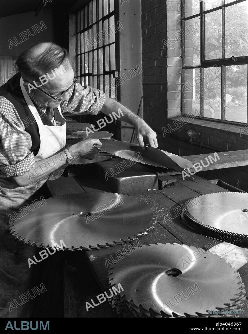 Tensioning circular saws at Slack Sellers & Co Ltd, Sheffield, South Yorkshire, 1963. In order for a circular saw to run true at speed, the saw blade should be slightly convex. The blade will revert to being flat when it spins at speed. In the photograph, the blades are checked to ensure that to correct curvature has been achieved in the tensioning process.