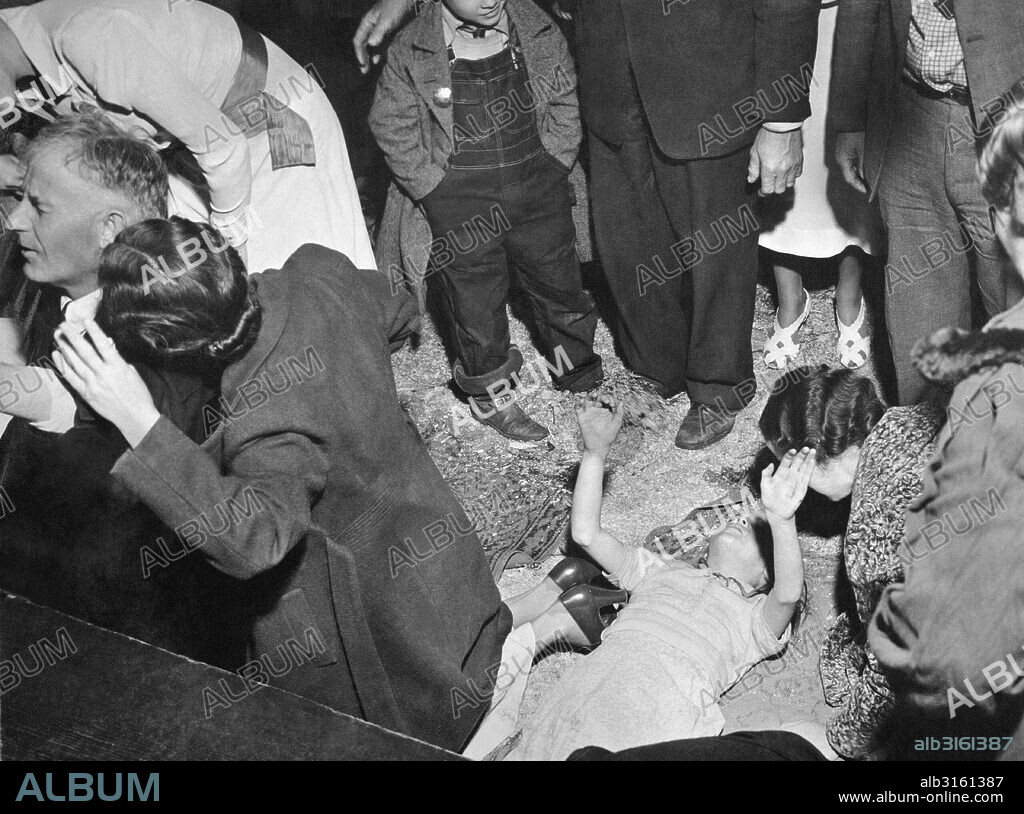 United States: c. 1938 Christian worshippers at a religious tent revival meeting responding to the call of the preacher.