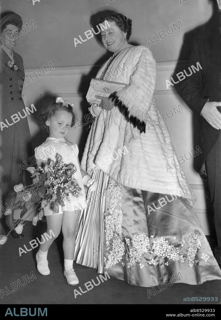 Orig. bildtext... QUEEN AND PRINCESS ELIZABETH AT ALBERT HALL. SANDRA WAS SHY... 4.5.49 The Queen and Princess Elizabeth this evening attenden a performance of Hiawatha at the Royal Albert Hall, London, in aid of the children's medical department of Battersea Central Mission. PHOTO SHOWS: Sandra Wakefield age 4 had the job of presenting a bouquet to the Queen on her arrival. Unfortunately Sandra walked right past the Queen at the first attempt, but afterwards, repented and carried out her job successfully. Orig. bildtext... Den här lilla flickan skulle lämna blommor till drottning Elizabeth, men var så upptagen av sina tankar att hon vandrade rakt förbi drottningen. Senare rättades misstaget. Anm. E Bowes-Lyon, 1900-2002, brittisk drottning 1936-1952 och maka till kung Georg VI, kallad drottningmoder när äldsta dottern tillträdde som drottning Elizabeth II 1952. Hermelinpäls Pärlhalsband Örhängen Siden Lång klänning Rosett i håret Handskar Kort kjol Sockar Buketter Liljekonvaljer Rosor Leenden Allvar CD514 persons: SANDRA WAKEFIELD;ELIZABETH, DROTTNING AV STORBRITANNIEN sites: LONDON;STORBRITANNIEN.