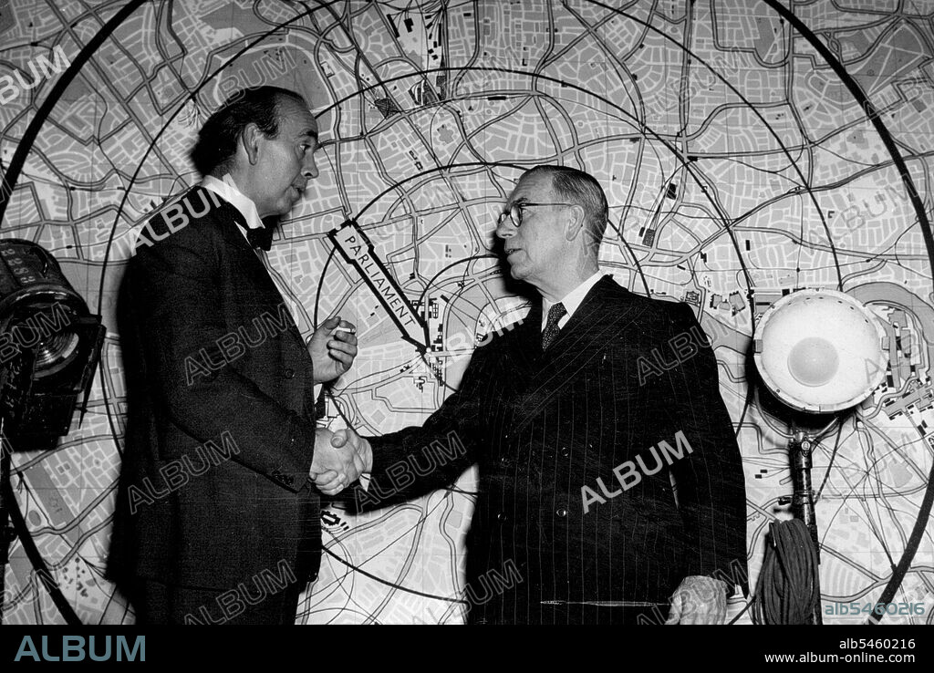 Premier Meets Prime Minister: The Rt. Hon. E.N. Hanlon (Wearing glasses), Premier of Queensland, Australia, shakes hands with actor-playwright Ronald Adam on the set of Seven Days to Noon: at Shepperton (Middlesex) film studios. Mr. Hanlon,who was on a tour of the studios during which he addressed the workers, watched directors John Boulting shooting scenes for 'Seven Days to Noon.' Afterwards he lunched with Mr. Adam who, in that film plays the Prime minister of Britain (1952). November 28, 1949. (Photo by Reuterphoto).