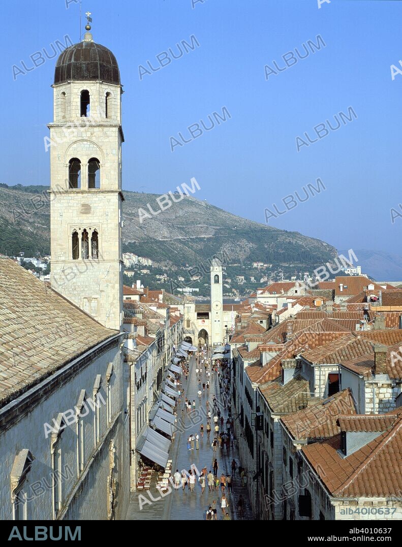 Stradun, Dubrovnik's main street, Croatia. The Adriatic port of Dubrovnik was founded by Roman refugees in the 7th century, and came under Byzantine rule after the fall of the Roman Empire. The city developed into a trading power and was an important centre of Slavic art and literature in the 15th-17th century. From the 14th century Dubrovnik was an independent city state, but it fell to Napoleon in 1808, after which the city passed to Austrian administration in 1815 and Yugoslavian in 1918. Dubrovnik was bombarded by the Serbs during Croatia's struggle for independence in 1991-1992. The bell tower of the Franciscan monastery is in the foreground. Originally built in the 14th century, in common with many of the city's buildings it had to be rebuilt after a devastating earthquake struck in 1667.
