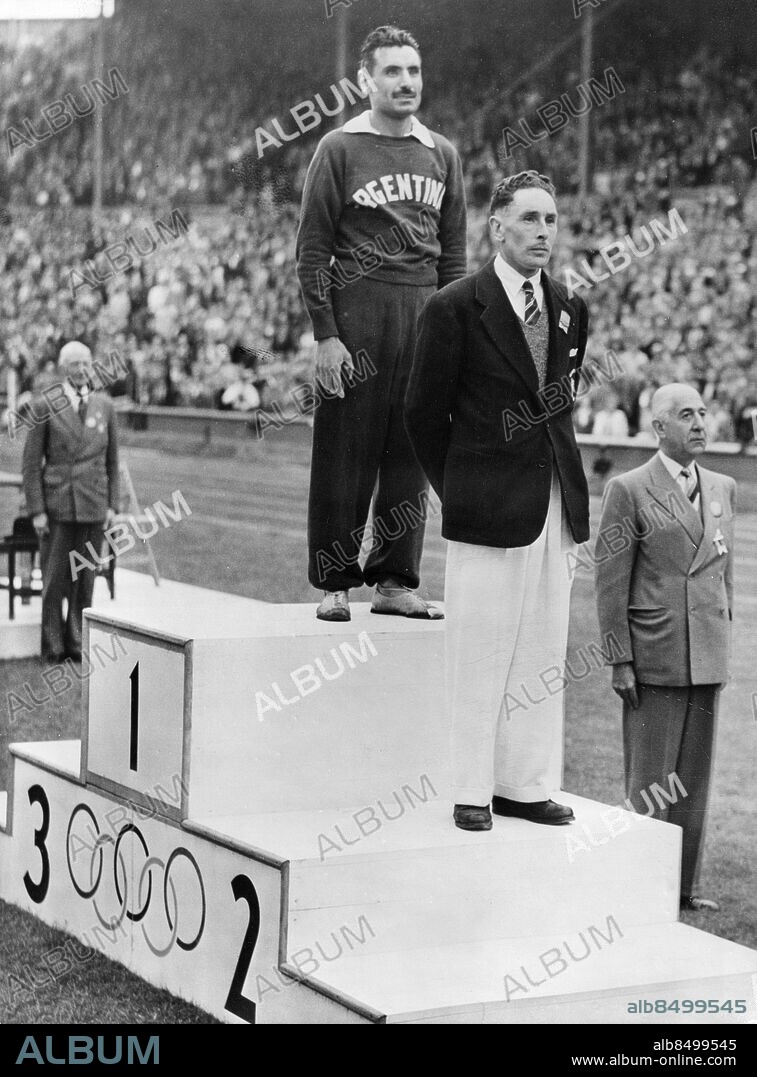 STORBRITANNIEN LONDON 1948-08-08.. Två löpare på prispallen på Wembley Stadium efter maratonloppet vid de olympiska sommarspelen 1948. Delfo Cabrera, Argentina, vann guld på tiden 2 tim 34 min 51.6 och tog därmed Argentinas första guldmedalj under spelen. Tom Richards, Storbritannien, kom tvåa och Etienne Gailly, Belgien, kom trea, men kunde inte närvara vid prisutdelningen eftersom han kollapsade efter loppet.. Foto: International News Photos / AB Text & Bilder / SVT / Kod: 5600. Engelsk originalbildtext.. Mapp: O.S. i London 1948: Marathon-loppet(Segrare: Cabrera, Argentina) I:275p. Prisutdelningar Prispallar Vinnare Segrare.