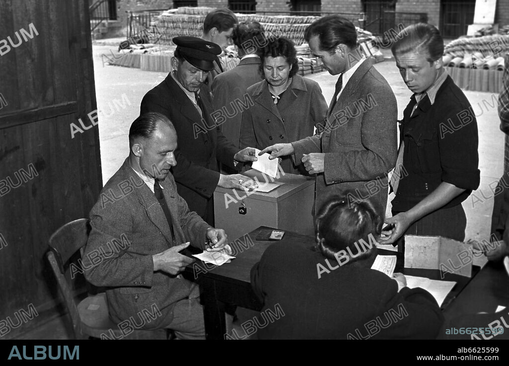 Workers of the Reichsbahn during the ballot vote about the continuation of the strike standing next to the ballot box in West Berlin, photograph taken on 02 June 1949. The whole railway operations and infrastructure of Berlin were subordinated to the East German State Railway (Deutsche Reichsbahn, DR) of the Soviet zone of occupation until 1949. On 21 May 1949, the Unabhängige Gewerkschaftsopposition UGO in the West sectors called upon to strike. Around 13.000 Reichsbahner (workers of the East German State Railway) living in West Berlin stopped work and fought for a payment in Westmark. Photo: zbarchiv - BLOCKED FOR PICTURE TRANSMISSION. 02/06/1949