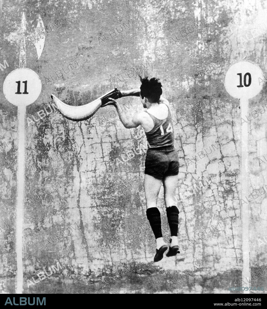 A HIGH FLIER IN THE WORLD'S FASTEST GAME. : Photo Shows: A remarkable action photograph of Alvaraz, a crack Cuban jai-alai player in the air while making a hit during a match at Miami, Florida. Jai-alai is a combination of tennis and handball and calls for a degree of accuracy and precision little known in the sports world. It is considered the fastest game in the world. United States 1931.