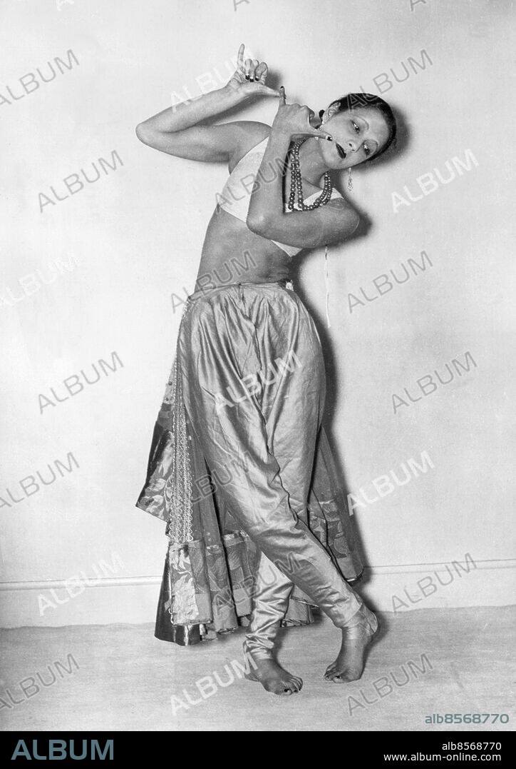 Orig. bildtext... BRAHMINS DAUGHTER ASKED TO GO ON STAGE. So magnificent was her reception in London of Menaka a beatiful Indian dancer, by a mixed English and Indian audience that she has been asked to appear on the stage Menaka is the daughter of a Brahmin, who was one of the best known men in Bombay. Picture taken at her London hotel shows:- An original 'Krishna' dance the 'Mudra' or 'Sign of the Flute' Anm. Halsband Barfota CD461 sites: LONDON;INDIEN*;STORBRITANNIEN.