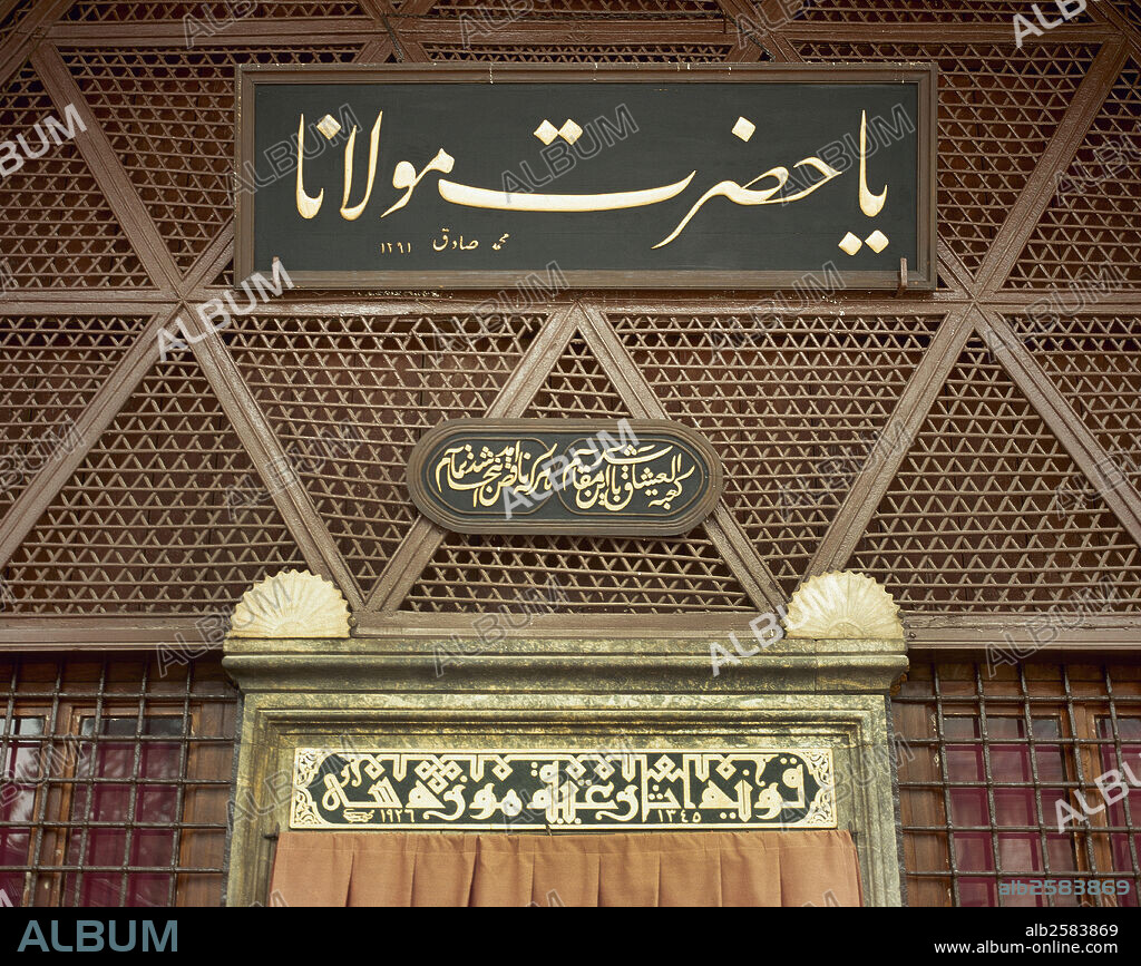 Arabic calligraphy (top and center) and Kufic script (bottom). Entrance to the Monastery of Rumi Mevlana. The taliq inscription above the door was composed by calligrapher Mehmed Sadik. It reads: "This place is the Qa'aba of lovers; he who comes here lacking is made complete". Konya. Turkey.