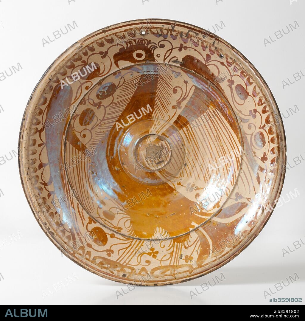 Fuente (recipiente), Siglo XVII, Cerámica (loza decorada con reflejos metálicos, umbo central y águila explayada, rodeada de hojas acorazonadas y cenefa de la ungla (uña)), de Manises o Valencia (Valencia), Diámetro: 38 cm.