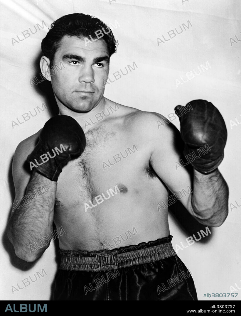Schmeling wearing boxing trunks and gloves, 1938. Maximillian Adolph Otto Siegfried "Max" Schmeling (September 28, 1905 - February 2, 2005) was a German boxer. Starting his professional career in 1924, Schmeling came to the United States in 1928. He became the first to win the heavyweight championship by disqualification in 1930, after opponent Jack Sharkey knocked him down with a low blow in the 4th round. He retained his crown successfully in 1931 by a TKO victory over Young Stribling. A rematch in 1932 with Sharkey saw the American gaining the title from Schmeling by a controversial 15 round split decision. In 1933, Schmeling lost to Max Baer by a 10th round TKO. The loss left people believing that he was past his prime.  In 1936, he knocked out American rising star Joe Louis, placing him as the number one contender for Jim Braddock's title, but Louis got the fight and knocked Braddock out to win the championship in 1937. Schmeling finally got a chance to regain his title in 1938, but Louis knocked him out in one round. During WWII, Schmeling served with the German Air Force (Luftwaffe) as an elite paratrooper. After the war, he mounted a comeback, but retired permanently in 1948. He  died in 2005 at the age of 99. In 2003, he was ranked 55 on The Ring magazine's list of 100 greatest punchers of all time. Photographed for the New York World-Telegram and the Sun Newspaper by William C. Greene, 1938.