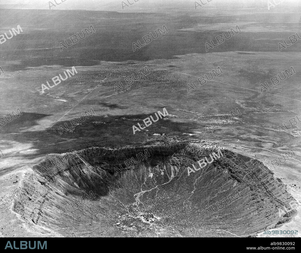 Winslow, Arizona circa 1935, An aerial view of the Meteor Crater, caused by a meteor hitting there 200 years ago. The dark area is from a passing cloud.