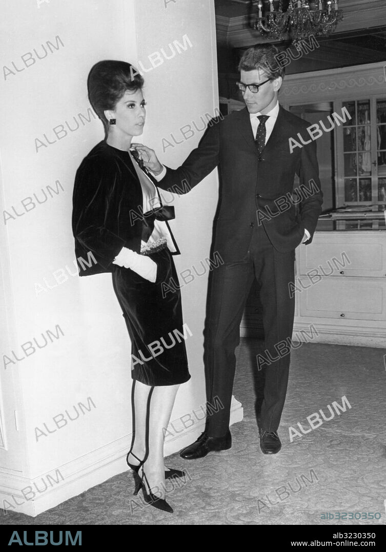 Orig. bildtext... YVES ST. LAURENT SHOWS HIS AUTUMN COLLECTION IN LONDON. PHOTO SHOWS: Yves St.Laurent - the famous young French fashion designer - makes a final adjustment on the smart black velvet suit, worn with a white embroidered satin blouse, before a display of his latest creations in London. Anm. Modekungar Sammet Blusar Kreatörer Inspektioner Dräkter Tudelade dräkter Mannekänger Rosetter Saint Laurent, Yves, f. 1936, fransk modeskapare, designer vid Dior 1957-61, från 1962 med egen verksamhet. CD244 persons: Yves Saint Laurent sites: LONDON ;STORBRITANNIEN ;FRANKRIKE*.