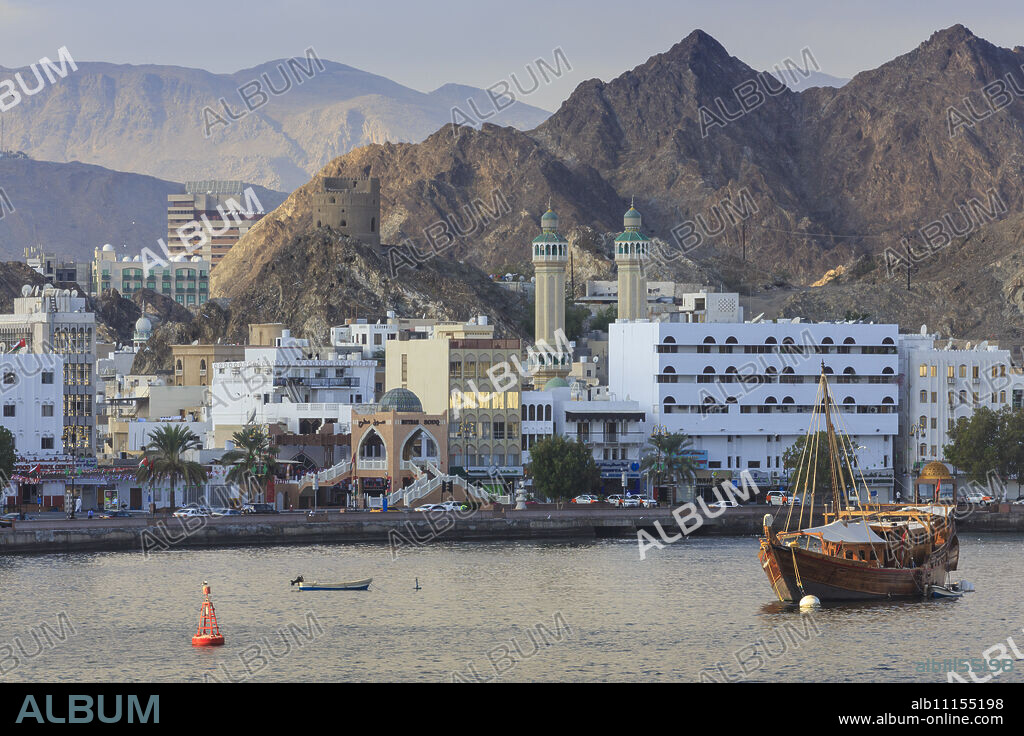Mutrah Corniche and entrance to Mutrah Souq, backed by mountains, viewed from the sea, Muscat, Oman, Middle East.