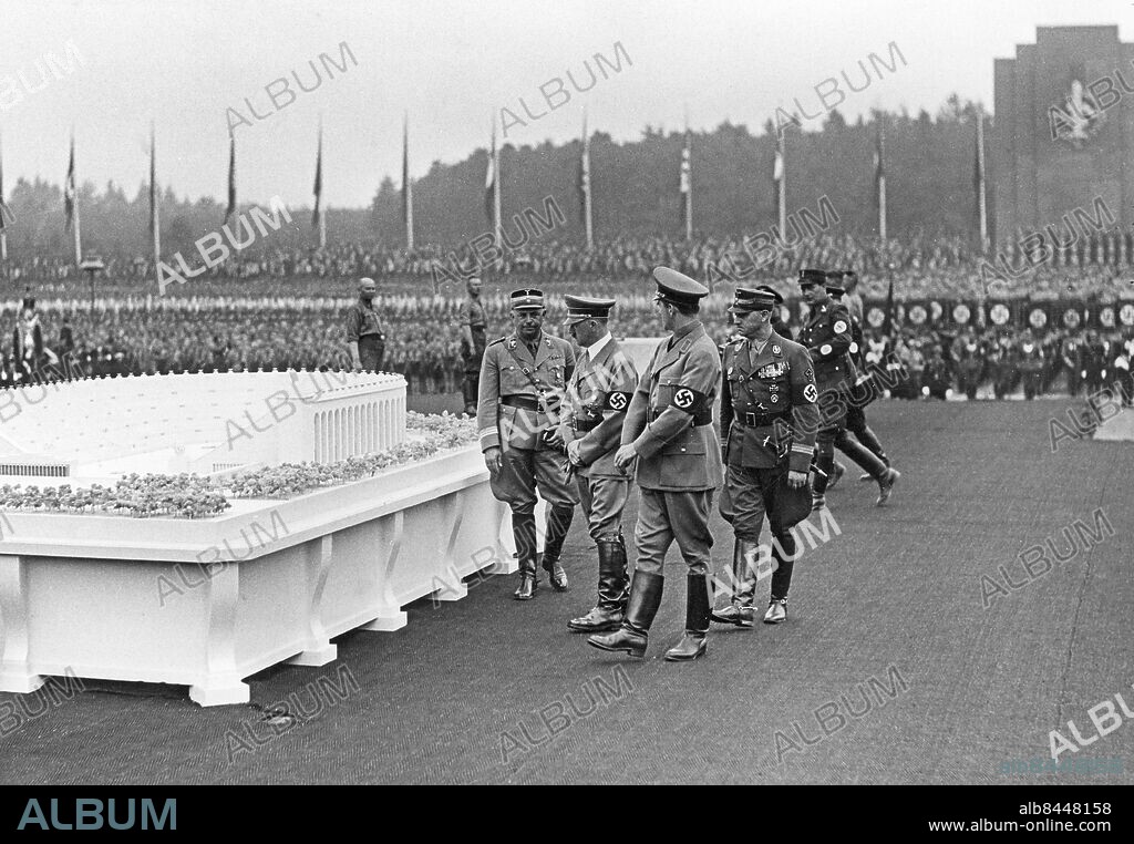 TYSKLAND NÜRNBERG 1937-09-09. Orig. bildtext... GRUNDSTEINLEGUNG FÜR DAS GRÖSSTE STADION DER WELT. Zusammen mit der Eröffnung der NS-Kampfspiele im Nürnberger Stadion am Donnerstagvormittag legte der Führer dort den Grundstein für das "Deutsche Stadion", das das grösste in der Welt sein wird. Unser bild zeigt: Der Führer besichtigt nach seinem Eintreffen das Modell des Stadion-Neubaues. Neben Adolf Hitler Reichsminister Kerrl, Stabschef Lutze und der Architekt, Speer. Foto: Scherl Bilderdienst / AB Text & Bilder / SVT / Kod: 5600 Mapp: Nürnbergs stadion (Tyskland) 525 G Anm. Deutsches Stadion, arkitekt Albert Speer, var tänkt att bli världens största idrottsarena. Arbetet påbörjades i september 1937 men blev aldrig färdigbyggt. Modeller Idrottsanläggningar persons: HANNS KERRL;ADOLF HITLER;VIKTOR LUTZE;ALBERT SPEER sites: TYSKLAND;NÜRNBERG.