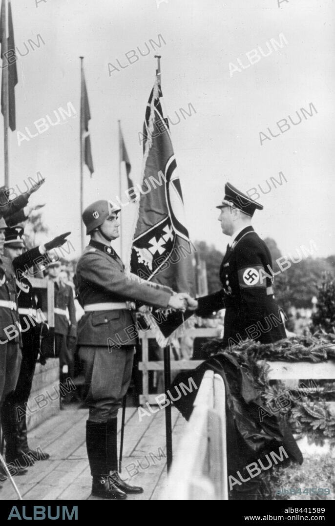 Orig. bildtext... DIE FEIERLICHE FAHNENÜBERGABE AN DANZIGS SS-HEIMWEHR Auf dem Danziger Maifeld jubelten am Freitag Hunderttausend Danziger der 1500 Mann starken SS-Heimwehr Danzig zu, die die deutsche Stadt als Abwehreinrichtung gegen die ständigen polnischen Kriegsdrohungen geschaffen hat und der and diesem Tage durch Gauleiter Forster die von ihm gestiftete Fahne verliehen wurde. -Unser Bild zeigt die Uebergabe der Fahne der SS-Heimwehr durch Gauleiter Forster an ihren Kommandeur SS-Obersturmbannführer Götze. 19.8.39. Orig. bildtext... DANZIGS HEIMWEHR MARSCHIERT! Selbstschutz sichert die deutsche Stadt. Danzig erlebte gestern einen stolzen Tag. Unter begeisterter Anteilnahme der Bevölkerung trat zum ersten Male Danzigs SS.-Heimwehr an, die jetzt zum Schutze der alten Hansestadt gegen die ständigen polnischen Kriegsdrohungen gebildet wurde. Bei ihrem Aufmarsch auf dem Maifeld übergab Gauleiter Albert Forster der Truppe die Fahne, die künftig dem jungen Aufgebot der Danziger Freiwilligen vorangetragen werden wird. U.B.: SS-Obersturmbannführer Götze (links) der Kommandeur der Danziger Heimwehr, nimmt aus den Händen des Gauleiters Forster die Fahne entgegen. 19.8.39. Anm. A Forster, 1902-1952, tysk nazistisk politiker, ståthållare i Fristaten Danzig 1930-1945, avrättad efter andra världskriget. Danzig - tyskdominerad fristat 1919-1939 under NF:s beskydd, Polen svarade för utrikespolitiken. Fanor Hakkors Hitlerhälsningar Nazisthälsningar Profiler Stövlar CD631 persons: HANS FRIEDEMANN GOETZE;ALBERT FORSTER sites: TYSKLAND*;DANZIG.