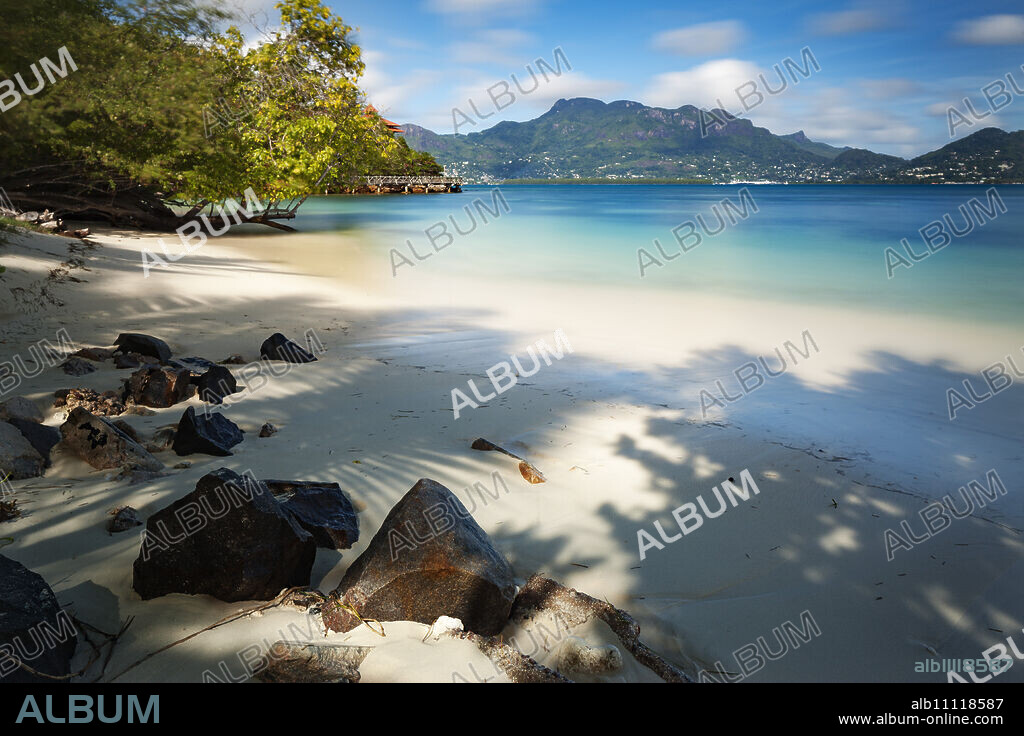 A deserted Seychelles beach with the calm still waters of the Indian Ocean beyond, Seychelles, Indian Ocean, Africa.
