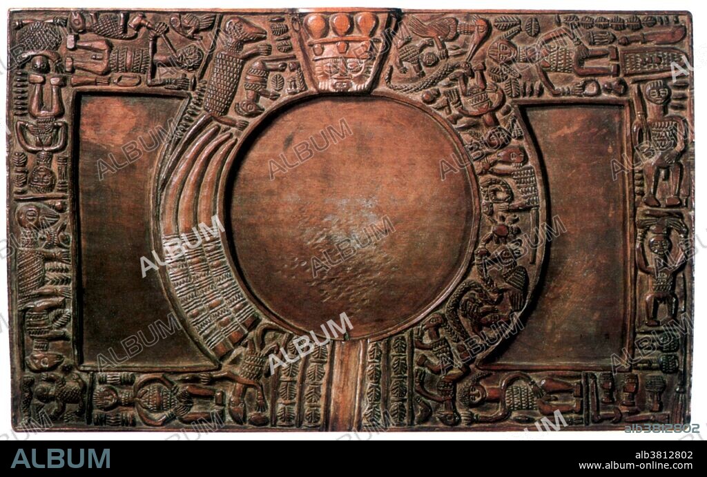The heart of Yoruba religion is Ifa, the Yoruba deity of divination who solves problems, provides comfort, and explains the ways of the gods. Individuals take direction and consolation from the Ifa diviner known as Babalawo, whom they have consulted to resolve a particular problem. The Babalawo has a set of ritual objects that are necessary for him to seek guidance from the gods and the Opon Ifa or divination tray is the most prominent. The flat center section is encircled by a number of Yoruba symbols reflecting deities as well as scenes taken from Yoruba life. The face of Eshu is placed at the top to carry the message to the gods and to lend his force to the divination. The diviner would cast cola nuts and read them as they fall and make a series of marks in a thin layer of sand placed in the round center section of the tray. No photographer credited, undated.