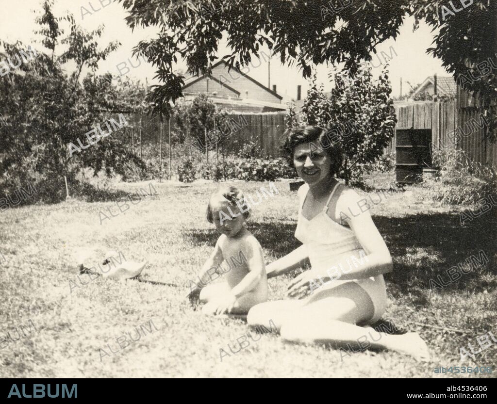 Photograph - Eileen & Susan Leech Sitting Next to Sprinkler in Backyard, Frankston, circa 1954, Photograph of Eileen Leech and her daughter Susan sitting next to a sprinkler in their bathers in the backyard of their home in Sandringham, Melbourne, circa 1954. Susan had migrated with her parents Eileen and James Leech to Melbourne from England in 1953 and they returned to England in 1956. The family first lived at 19 Nelson Street Sandringham and then moved for the majority of their stay.