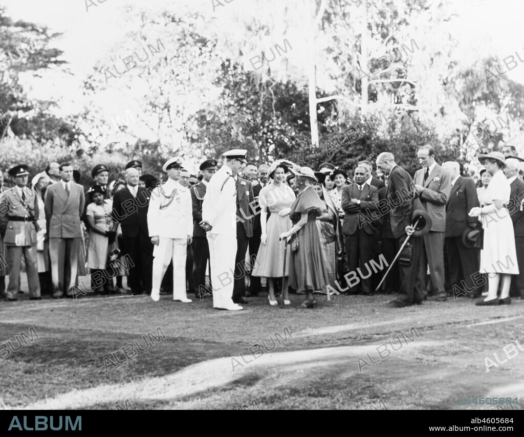 Kenya, Princess Elizabeth and The Duke of Edinburgh are speaking to Lady Lucie McMillan, widow of Lord McMillan. Behind them is a large group of guests of some 40 people watching the proceedings, many wearing uniforms, February 1952. 2001/090/1/4/1/19.