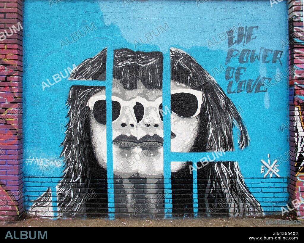 Pintura en blanco y negro de cara de mujer fragmentada con gafas, sobre fondo de tonos azules, graffiti mural, calle Selva de Mar, barrio Poblenou, Barcelona en 2016.