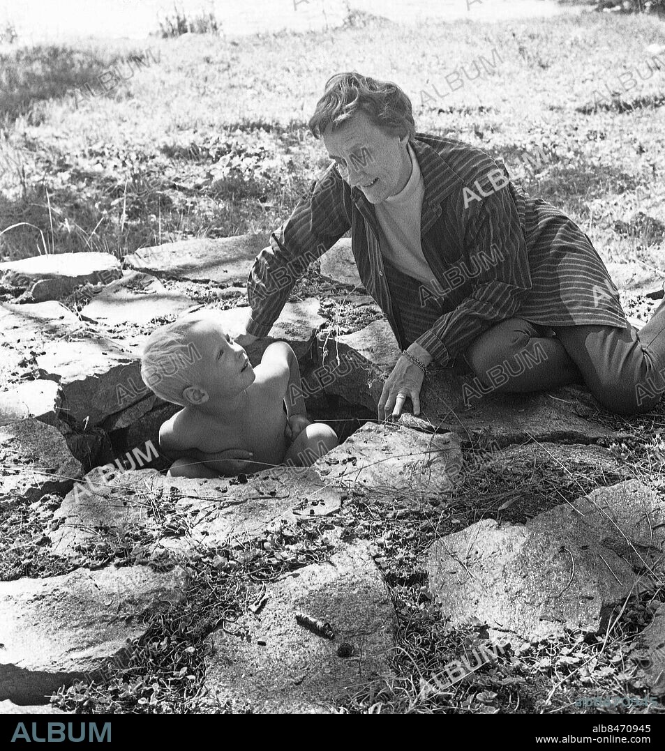 FURUSUND 1965-08-10.. BARNENS HALVTIMME. Radioprogram, reportage hos Astrid Lindgren i Furusund.. Sänt första gången 1965-08-22. Här ses författaren Astrid Lindgren leka med sitt barnbarn Karl-Johan vid en brunn.. Foto: Ulf Stråhle / SVT / Kod: 5600. Bild och reportage publ. i RiR 34/65 sid 8-10.. RiR 17738 sv/v neg. Barnbarn.