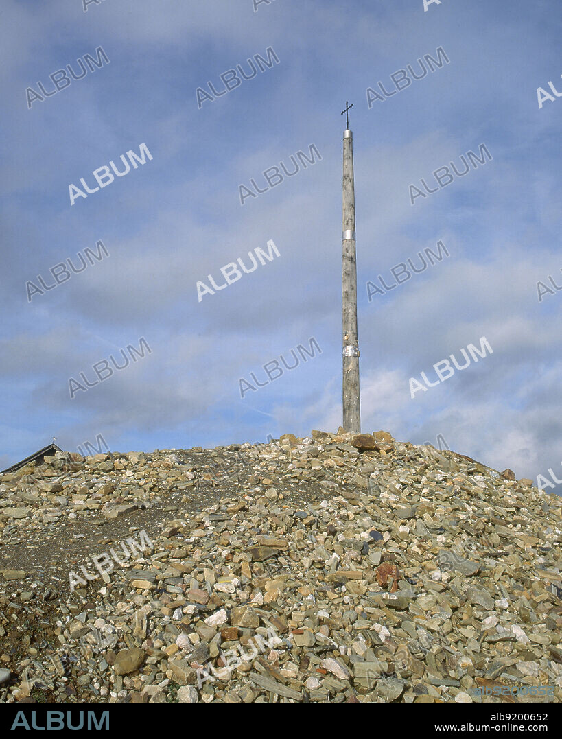 CRUZ DE HIERRO SOBRE UN MONTICULO FORMADO POR GUIJARROS QUE DEJAN LOS PEREGRINOS.