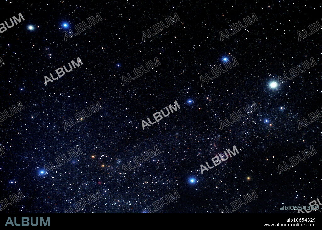 Auriga. Stars forming the northern constellation of Auriga (the Charioteer). North is at top. The band of stars that is the Milky Way passes through this constellation, seen as the slightly denser scattering of stars in the lower frame. Auriga is actually the grouping of seven stars at right. The three bright stars at left are the rightmost part of the constellation Gemini. In Auriga, there are four bright blue stars (three on the left, one on the right). The other 2 stars are the orange star below the right-hand blue star, and the bright white star above it. This white star is Capella (Alpha Aurigae, the Goat Star). Auriga is best seen in winter in the Northern Hemisphere.