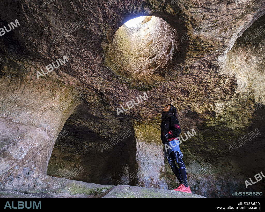 tourist observing a skylight, necropolis, Cala Morell, Ciutadella, Menorca, Balearic Islands, Spain.