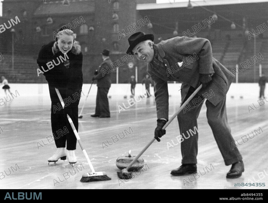 STOCKHOLM 1949-11-01.. Gun Hammarin, konståkerska, och Håkan Westergren, skådespelare, spelar curling på Stadions konstfrusna is.. Foto: Bertil Lindskog / AB Text & Bilder / SVT / Kod: 5600. Mapp: Svensk curling I:34 1/2A. Kvastar.
