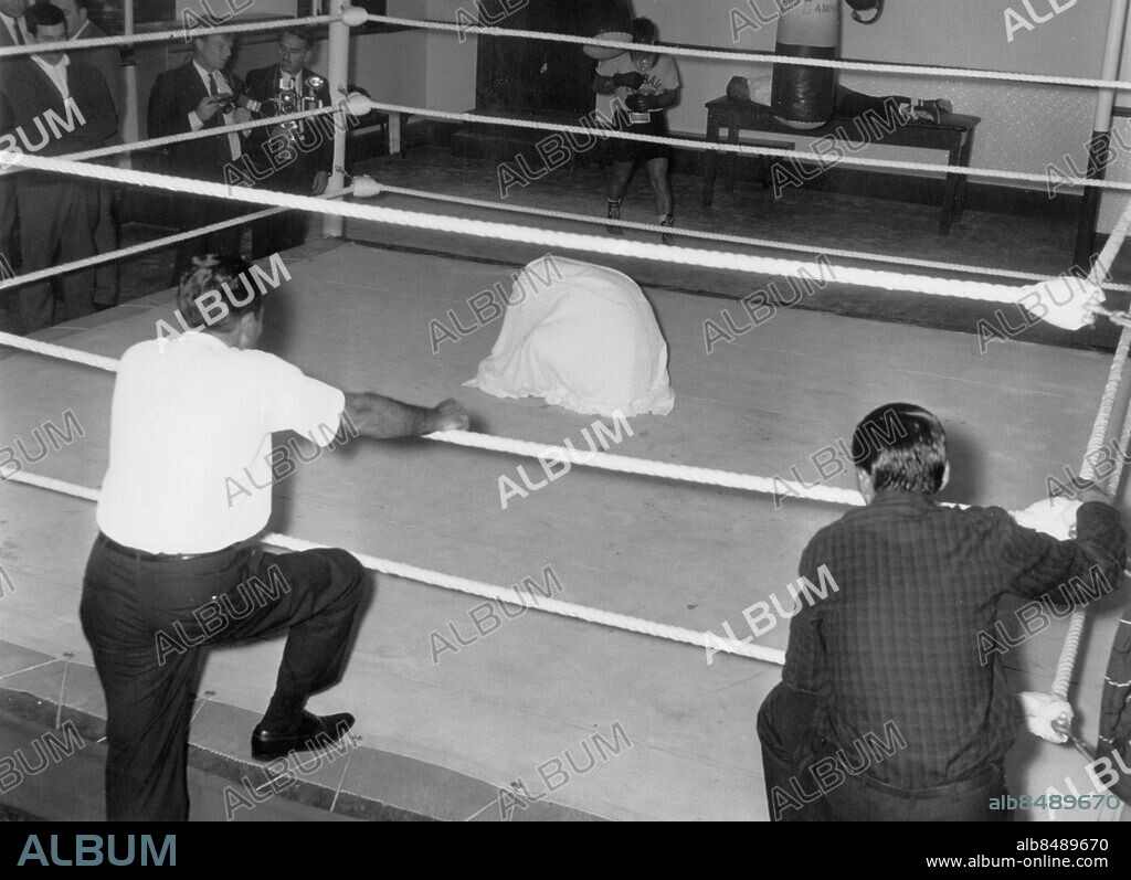 Orig. bildtext... London Mexican featherweight champ starts training. Vincente Saldivar the world featherweight boxing champion who meets Howard Winstone the british and european featherweight champion for a title fight at Earls Court on sept 17th. starts training at the British Board of Boxing Bontrol Gymnasium at Haverstock Hill, North London. Photo shows: Vicente Saldivar using a towel as a sweat tent Anm. träningslokal med boxningsring ryggbilder åskådare värme i mittpunkten fokus sites: STORBRITANNIEN;LONDON.