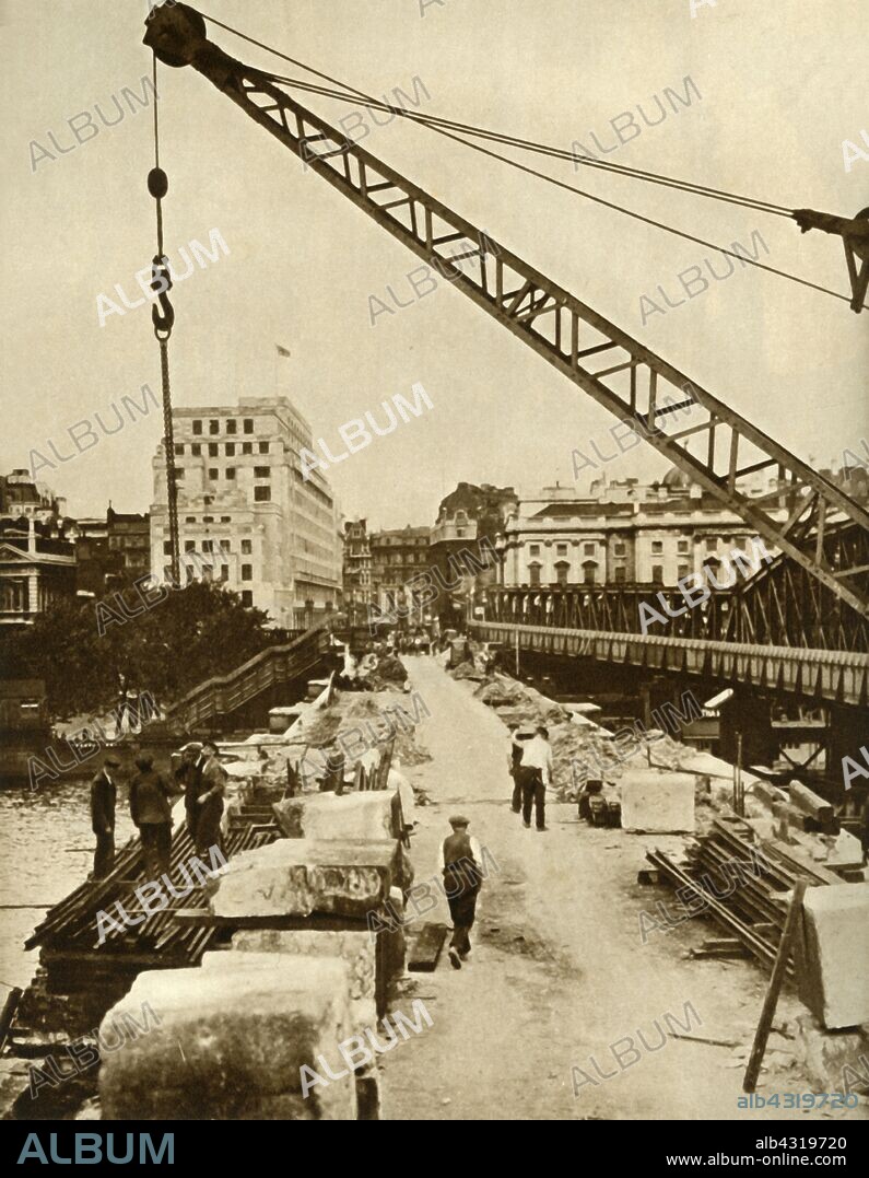 The rebuilding of Waterloo Bridge, London, 1934, (1935). London County Council demolished the old bridge which was damaged, and commissioned a new structure designed by Sir Giles Gilbert Scott. The project was placed on hold due to the Second World War. The only Thames bridge to have been damaged by German bombers during the war, it was not fully completed until 1945. From "The Silver Jubilee Book - The Story of 25 Eventful Years in Pictures". [Odhams Press Ltd., London, 1935].