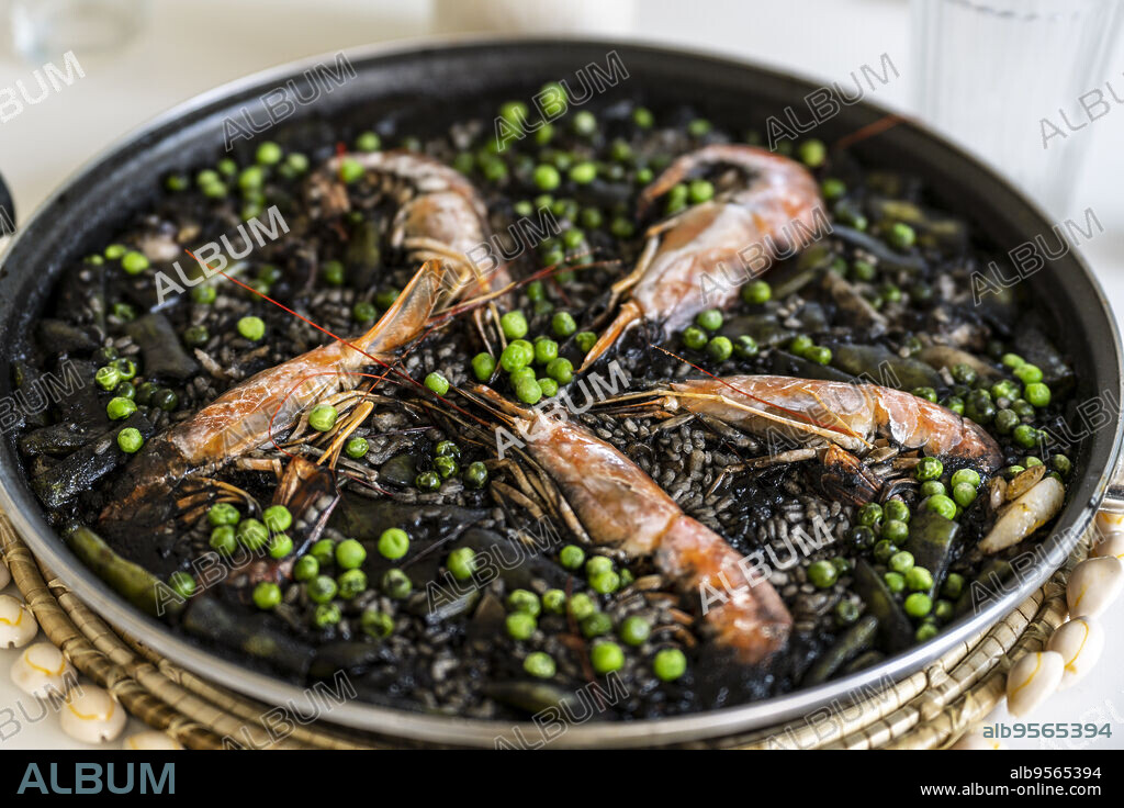 black rice paella with cuttlefish ink, prawns and peas, Majorca, Balearic Islands, Spain.