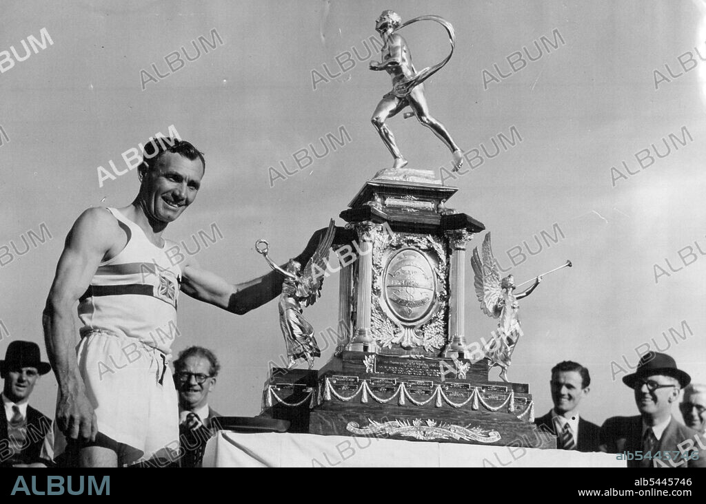 Holden Again Wins Windsor Chiswick Marathon Jack Holden with the marathon trophy after finishing at the Polytechnic Stadium, Chiswick, London to-day. Jack Holden of Tipton Harriers, last year's winner of the event, again won the Polytechnic Harriers Kinnaird Trophy marathon from Windsor to Chiswick, London, when to-day (Saturday) he covered the distance of more than 26 miles in 2 hours 42 minutes 52.4 seconds. A record number of 212 competitors were started from Windsor by Princess Elizabeth. June 18, 1949. (Photo by Reuterphoto).