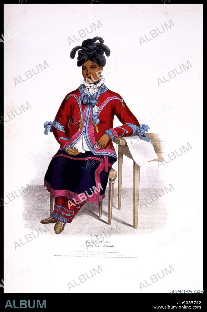 An Ojibway woman with left arm resting on a table on which is a paper with her name on it, spelled 'Thusick'. The Ojibwe (or Chippewa) are one of the largest groups of Native Americans in North America.
