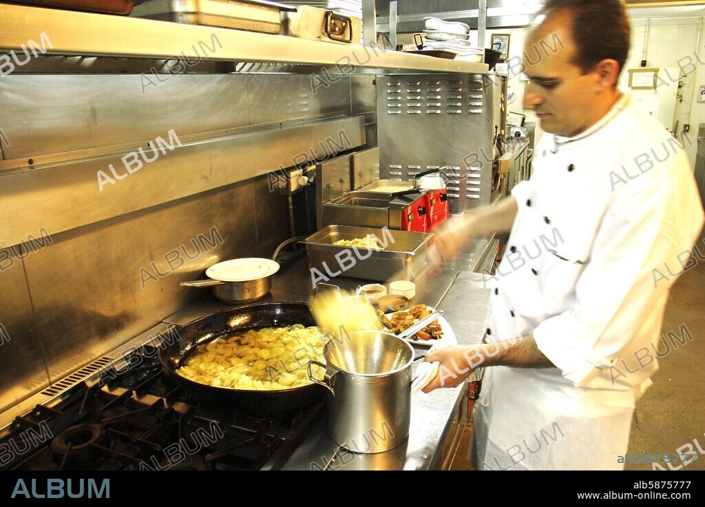 Bar - Restaurante "Teatriz"; jefe de cocina friendo las patatas para la confección de tortilla española.