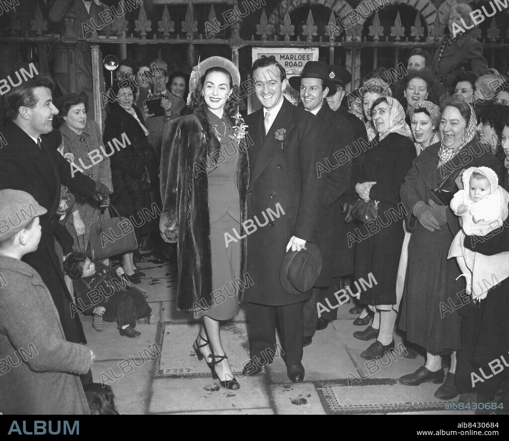 Orig. bildtext... DAVID NIVEN MARRIES IN LONDON Film star David Niven married Mrs. Hjordis Tersmeden, lovely auburn-haired Swede to-day at South Kensington Register Office. They met recently when a friend took Mrs. Tersmeden to see the filming of Bonnie Prince Charlie in which Niven plays the title role. They sail for New York in the Queen Elizabeth on Saturday. Mr. Niven is a widower. His wife, the former Miss Primula Rollo, died at Hollywood in May, 1946. Photo shows: David Niven and his bride surrounding by admiring crowds, including babies in arms as they leave South Kensington Register Office after the ceremony. Orig. bildtext... ROMANTISKT BRÖLLOP I LONDON Filmskådespelaren David Niven och fru Hjördis Tersmeden hyllas efter vigseln. Anm. Skådespelare Ansiktsuttryck Åskådare Leenden persons: David Niven ;Hjördis Tersmeden sites: STORBRITANNIEN ;LONDON ;SVERIGE*.