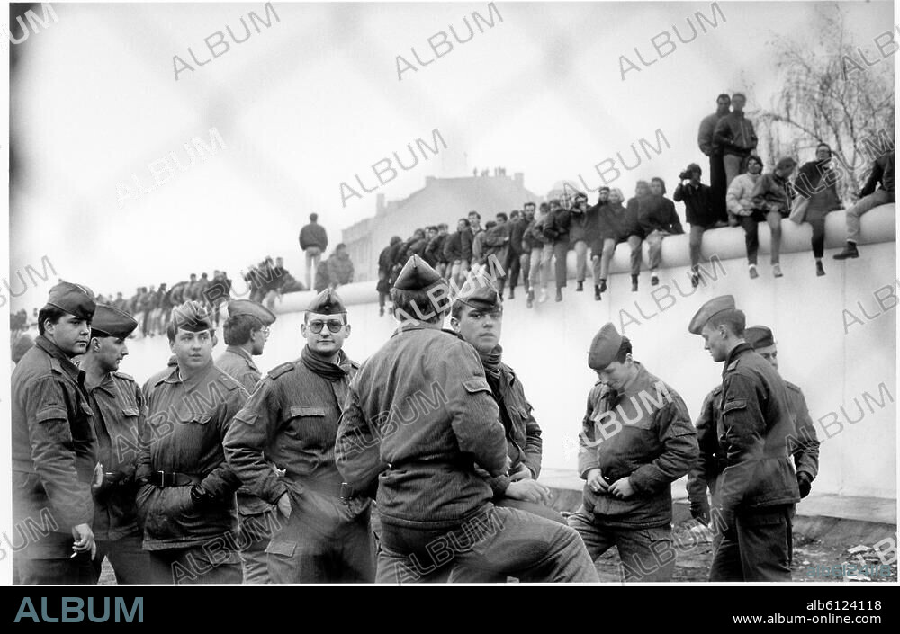 Berlin, 10./11. November 1989:. Nach Öffnung der DDR-Grenzen zum Westen (9.11.1989). Öffnung eines weiteren Übergangs am Potsdamer Platz. Berliner aus beiden Teilen der Stadt besetzen die Mauer; im Vordergrund DDR-Grenztruppen. Foto.