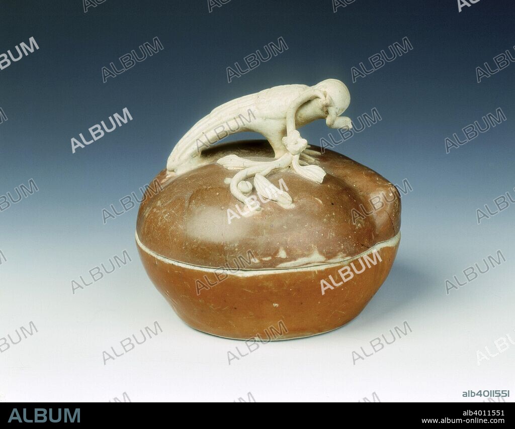 Peach shaped covered box with cafe au lait glaze and unglazed pigeon in relief, Ming dynasty, China, 16th century. A covered box of flattened peach form covered with a cafe-au-lait glaze of rather glassy golden tone. The top is surmounted by an unglazed pigeon holding a spray of leaves in its beak.