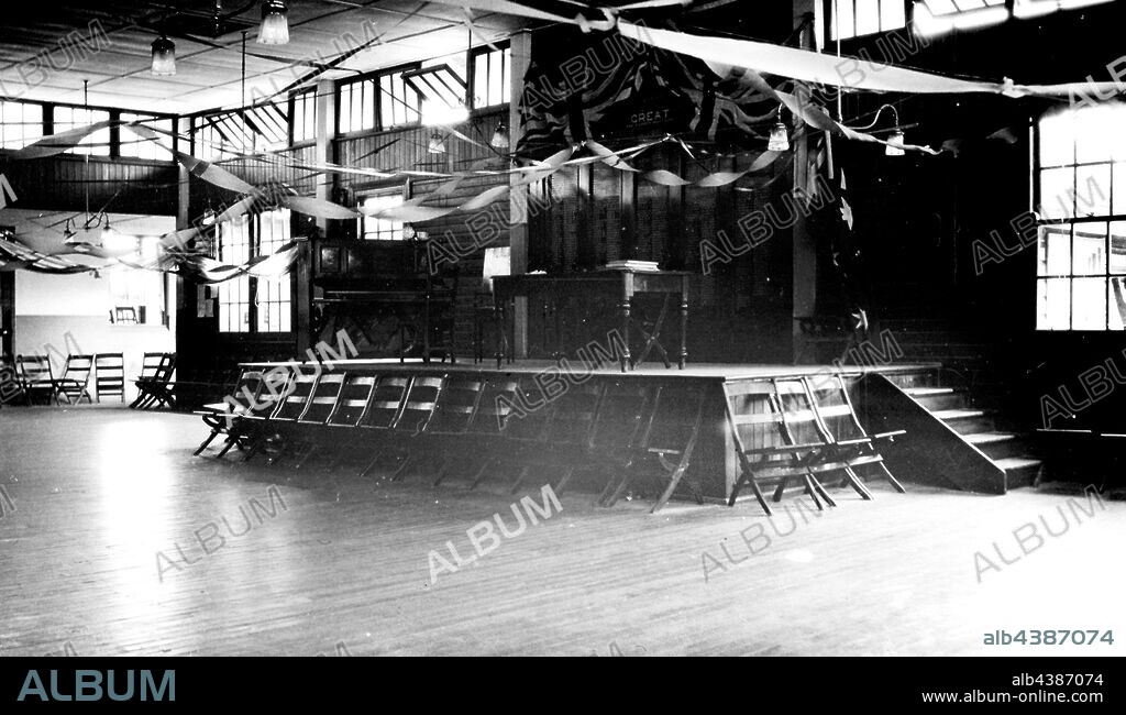 Negative - Hay, New South Wales, circa 1925, The assembly hall at the Hay War Memorial High School. A school ball had been held the night before and decorations are still in place. Behind the stage is a list of those from the Hay district who died in the Great War.