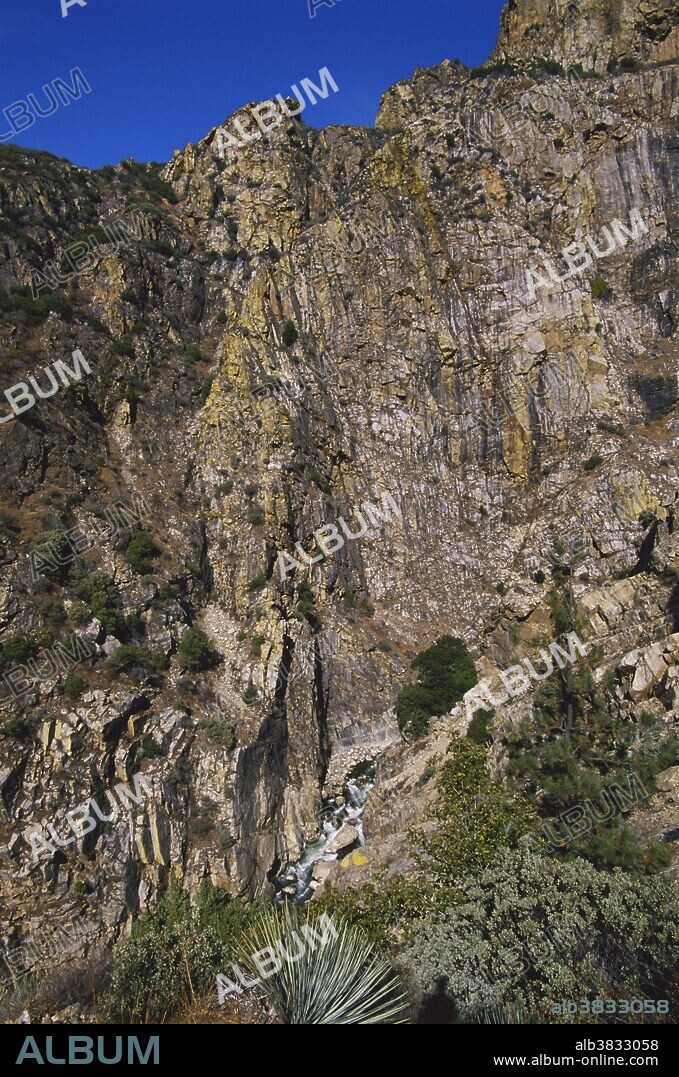 Near vertical granite walls tower above the South Fork of the Kings River in Kings Canyon National Park, California. Yellow lichens add color to the granite.