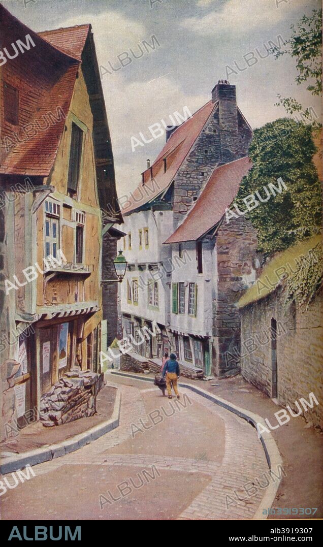 'Brittany. Within the turreted walls that enclose Dinan are many curious narrow streets, especially here near the Porte du Jerzual', c1920. Dinan is a town situated in the C¶tes-d'Armor department, Brittany. The oldest part of the town includes several 13th century buildings and walls. From Geographical Magazine, Volume 2, c1920.