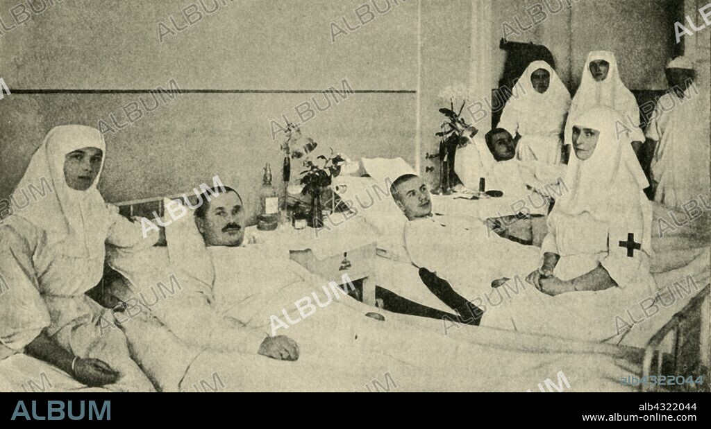 Tsarina Alexandra nursing wounded soldiers, 1914, (c1920). 'Imperial Nurses with the Russian Red Cross: the Tsarina (seated on the right) and her daughters nursing wounded soldiers from the eastern theatre of war'. Alexandra Empress of Russia (1872-1918), seen here with her daughters, Grand Duchesses Olga and Tatiana Nikolaevna, was engaged in charity work and served as a nurse during the First World War. From "The Great World War - A History" Volume II, edited by Frank A Mumby. [The Gresham Publishing Company Ltd, London, c1920].
