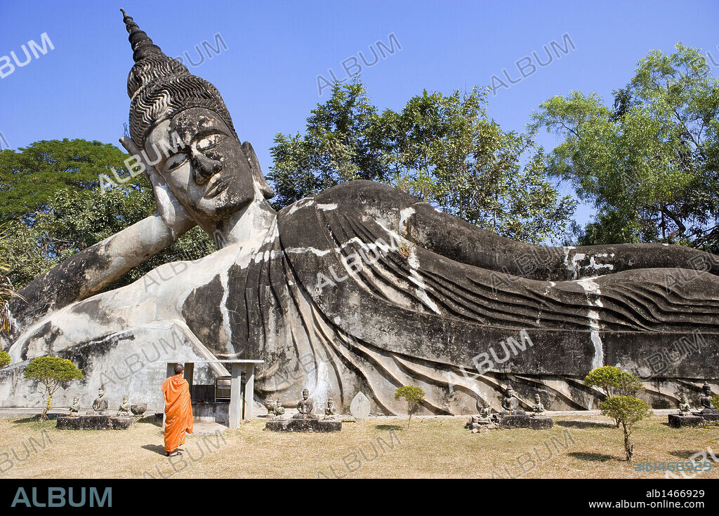 MONJE BUDISTA junto a la ESTATUA DE BUDA RECLINADO. PARQUE DE BUDA ("BUDDHA PARK"). Cercanías de Vientiane. Laos.