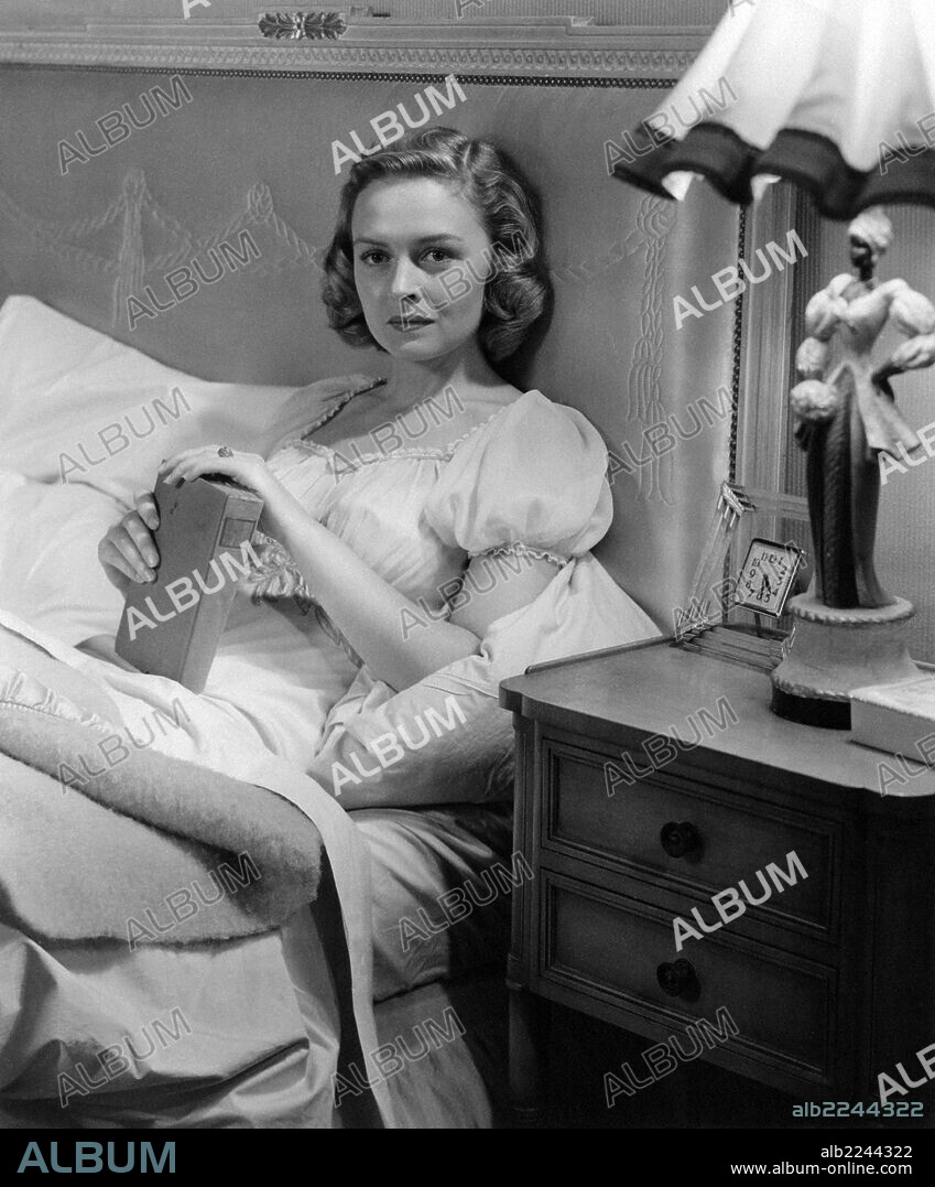 Donna Reed in Beyond Glory. American actress Donna Reed (Donnabelle Mullenger) lying in a bed holding a book in the film Beyond Glory. 1948.