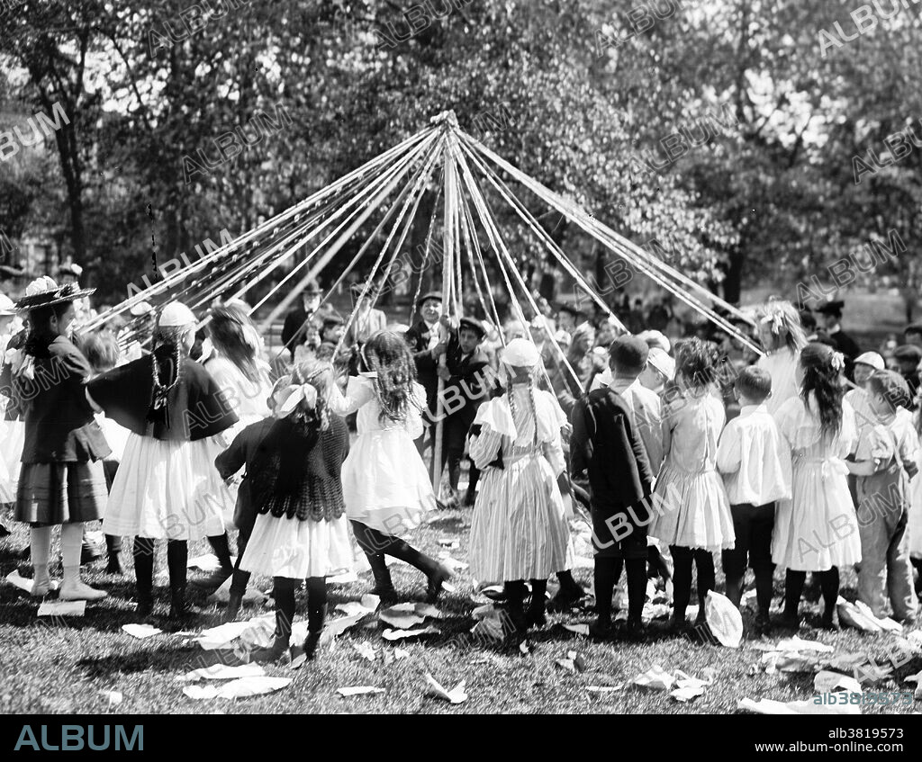 Entitled: "May pole dance, Central Park, New York." Maypole dancing is a form of folk dance from Germany, England, and Sweden. The most popular maypole dance consists of dancers that perform circle dances around a tall, garland-festooned pole (originally a live tree).The dancers move in a circle, each holding a colored ribbon attached to a much smaller pole. As they move around the pole, the dancers intertwine their ribbons either in a web around the pole or to plait it to the pole, itself. To unravel the ribbons, the dancers retrace their steps. Historians believe the first maypole dance originated as part of Germanic pagan fertility rituals. While dancers usually perform this dance in the spring on May 1 or May Day, those in Sweden perform it during their midsummer celebrations. Photographed by the Detroit Publishing Company, 1905.