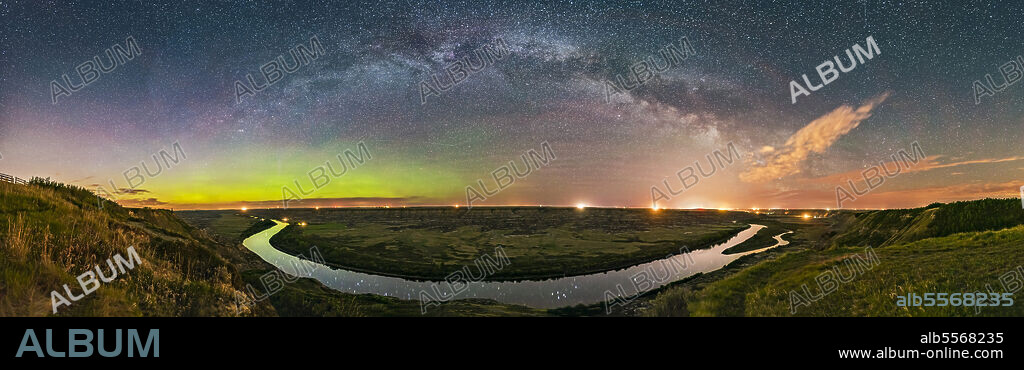 May 20, 2017 - The river of stars, the Milky Way, arching over the scenic bend of the Red Deer River, Alberta, Canada, from the Orkney Viewpoint overlooking the Badlands and river valley, in a 270 degree panorama. To the north at left, a weak aurora shines along the horizon. Bands of airglow also colour the sky to the east at centre, and perpetual twilight lights the sky at far left. To the south at right, the Milky Way becomes lost amid the light pollution from Drumheller, Alberta, made more obvious by some clouds drifting through. So this is a study in skyglows: aurora, twilight, airglow, Milky Way and urban skyglow, and of the contrast between the natural sky and light polluted sky. The most prominent stars reflected in the still waters of the river are the stars of Delphinus the Dolphin.